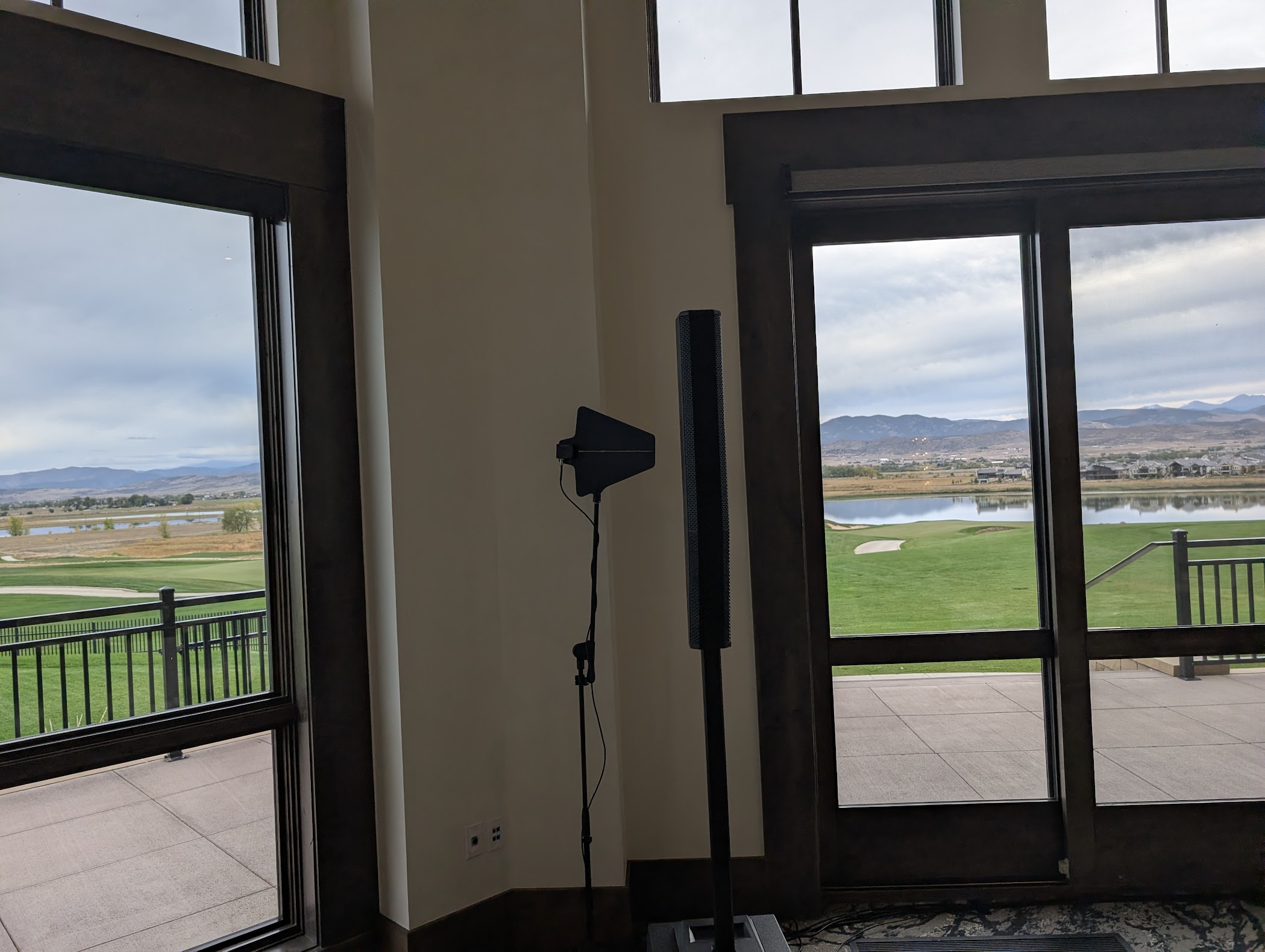 A speaker column and antenna stand tucked into a corner between windows