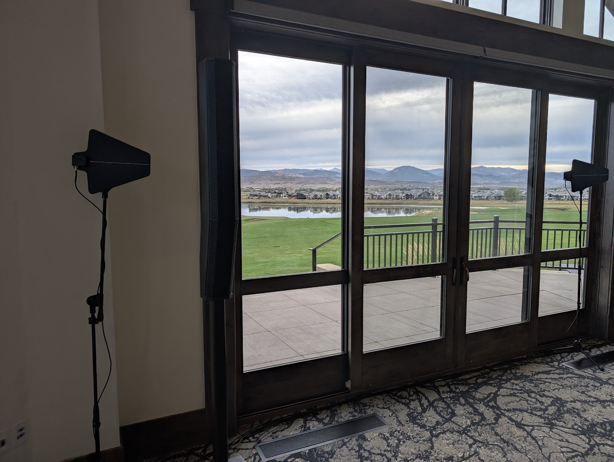 A slim speaker column and wireless antenna stands set up beside glass doors at a venue